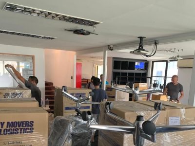 Commercial Move Packing Several movers are packing and organizing cardboard boxes and office furniture in a well-lit room.